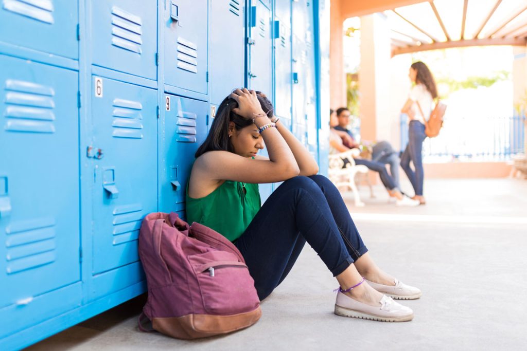 upset female teen at school locker